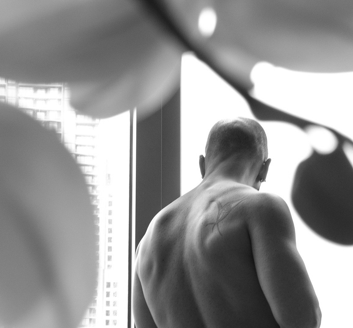 Troy seen from behind, looking out through a window in black and white