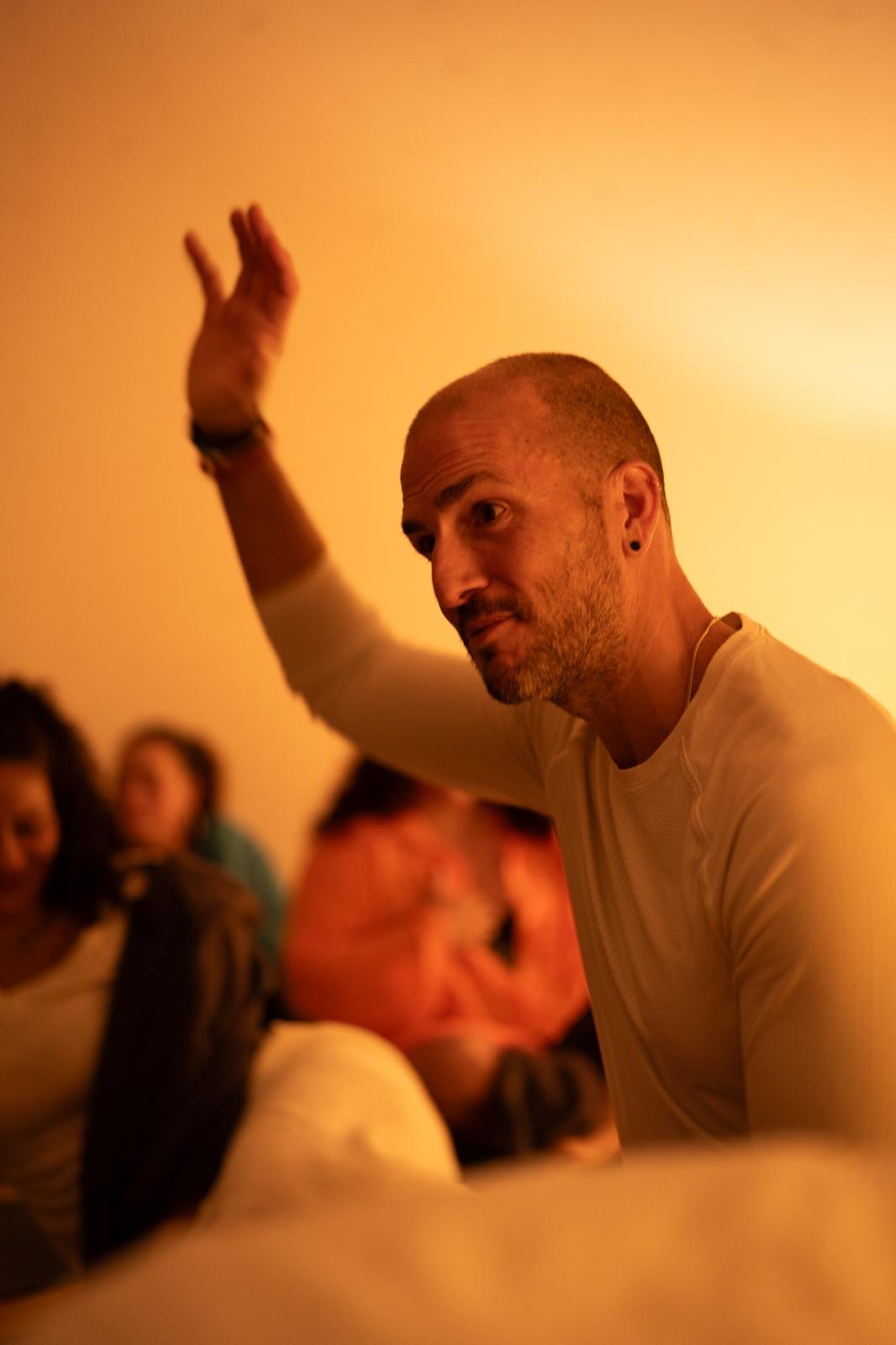 Troy Jason Valls leading a private group session, one hand raised