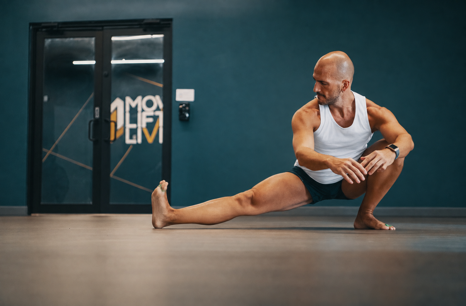 Troy in a deep lateral lunge on a studio floor, working slowly into the hip